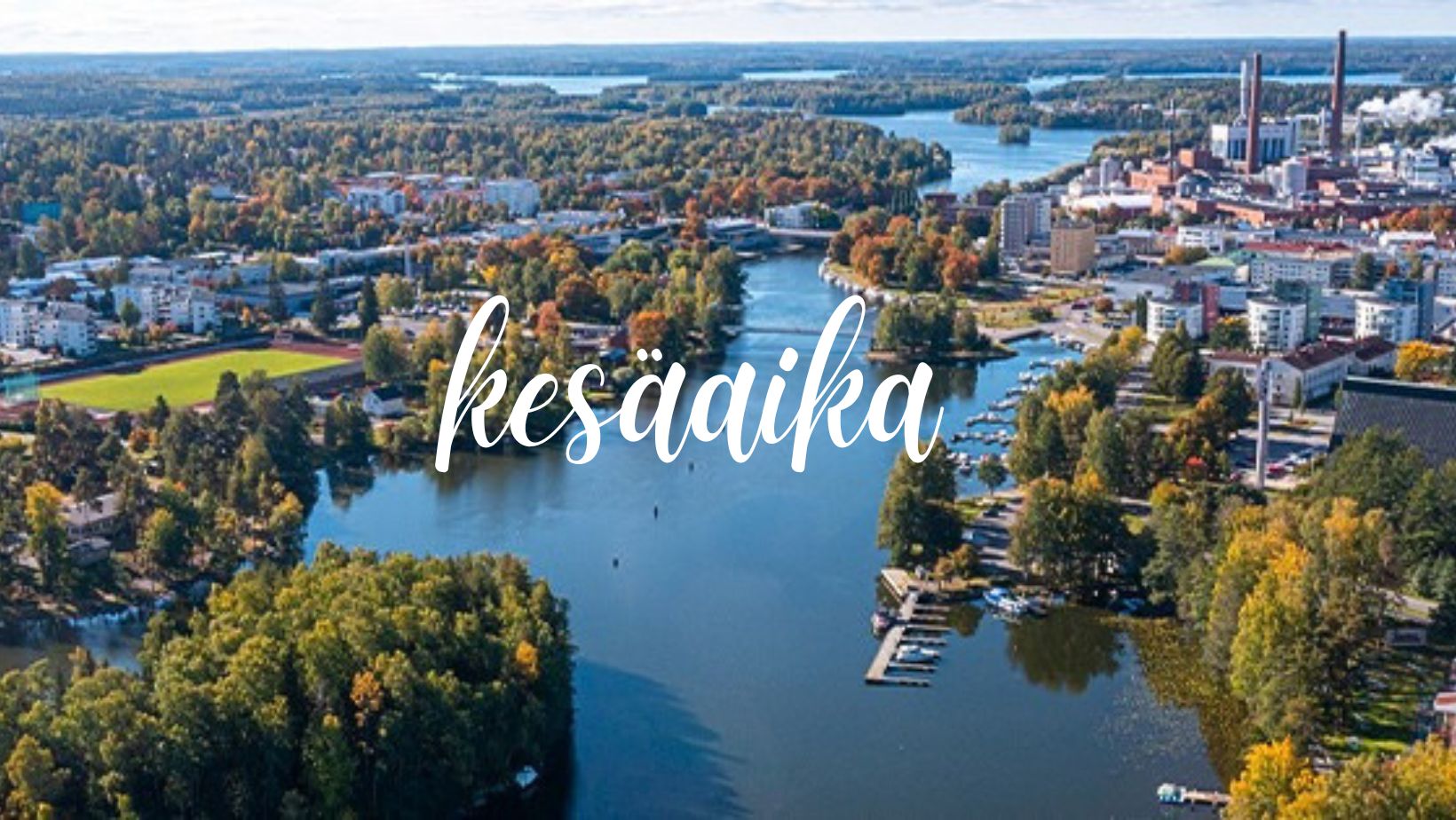 Ilmakuva Valkeakosken keskustan maisemista. Kuvassa on järvi, saari, puustoa sekä kaupungin erilaisia rakennuksia kuvattuna ilmasta käsin.